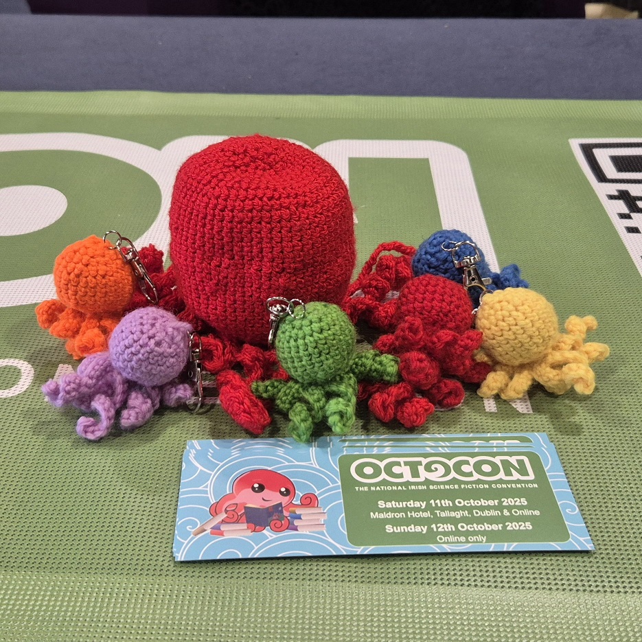 A large red crocheted Octo surrounded by baby Octos in rainbow colours.
