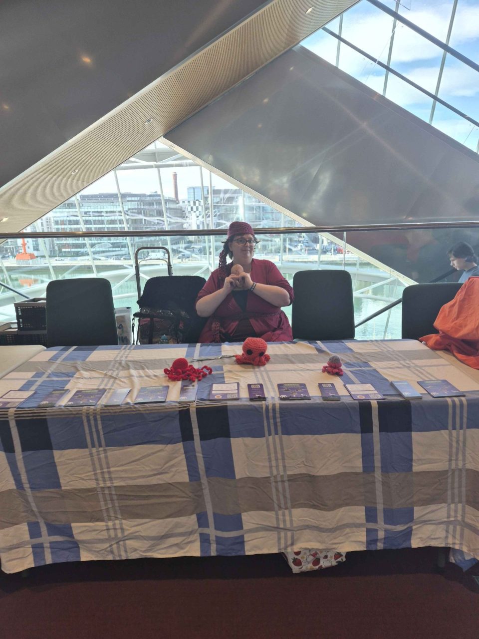 Kat Dodd crocheting at the Octocon table